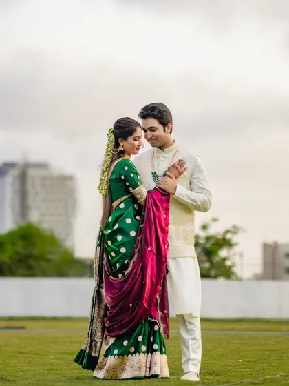 An intimate embrace in an open field, with the city skyline in the distance. This shot beautifully contrasts the couple's traditional attire with a modern landscape, symbolizing their journey together.