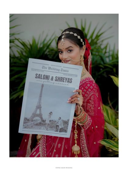 A creative shot of the bride holding a custom "Wedding Times" newspaper, a unique and personal touch to her wedding story.