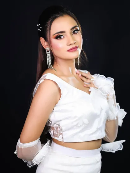 A three-quarter shot showing the full white ensemble with its delicate lace and ruffle details. The makeup is kept fresh and radiant.