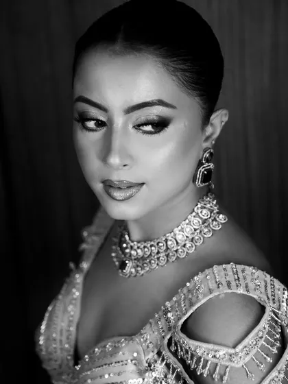A classic black and white beauty portrait. The soft lighting emphasizes the flawless makeup and intricate jewelry, resulting in a timeless and glamorous headshot.