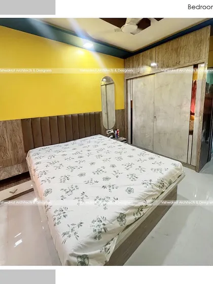 A bedroom design featuring a bright yellow accent wall and a mix of wood and laminate finishes on the furniture. This creates a cheerful and personalized space.