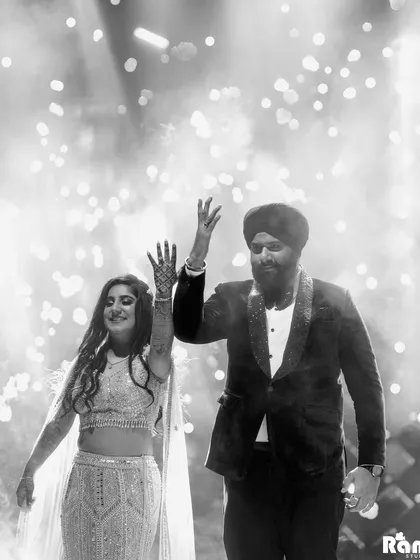 The energy of a grand entrance is electric. I captured this couple's joyous celebration, hands raised amidst a shower of cold pyro fireworks. This black and white candid shot freezes a moment of pure happiness and high energy, showcasing the lively spirit of a Punjabi wedding.