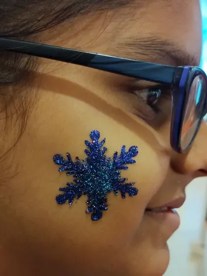 A perfect choice for a winter-themed party. This large, intricate blue snowflake glitter tattoo looks stunning on the cheek and is always a popular request during the holiday season.