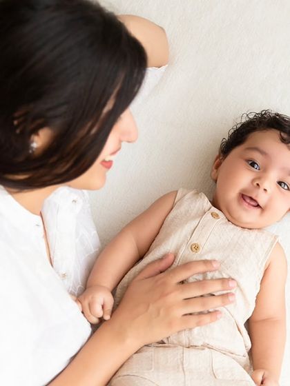 A mother looks down at her smiling baby during a simple and sweet milestone session.