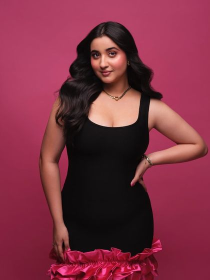 Styling Revathi Pillai in a chic little black dress with a fun, ruffled pink hem. This look is playful, stylish, and perfect for a personal or promotional photoshoot.