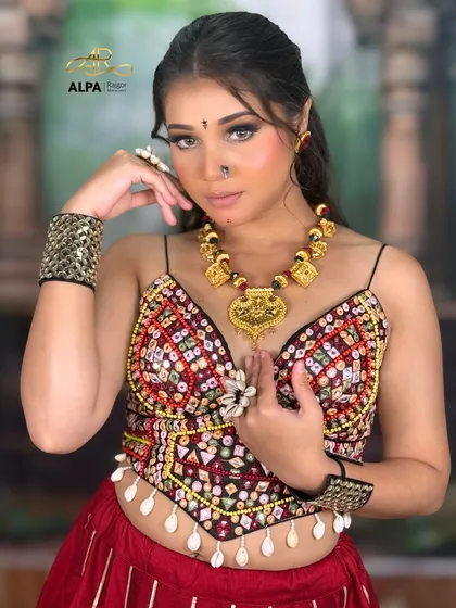 This pose shows off the intricate necklace and the detailed embroidery of the choli. The makeup enhances the model's features without overpowering the outfit.