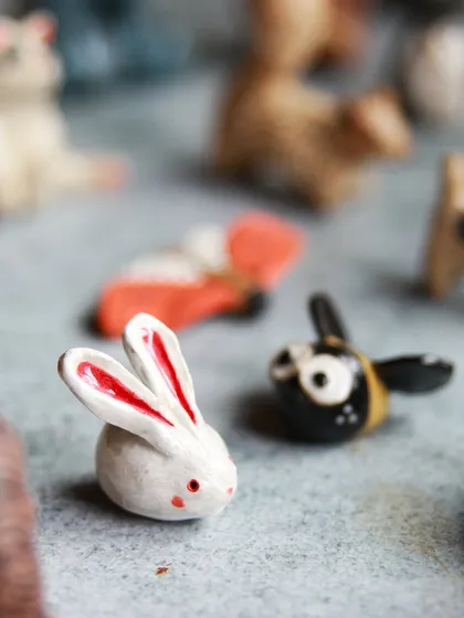 A tiny white rabbit with pink ears and a buzzing bee, showcasing the playful and imaginative possibilities of clay.