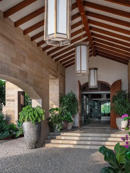 A view of the entrance porch, with its stone-clad archway and lush landscaping. We used antique pots and bougainvillea to add color and character to this impressive entryway.