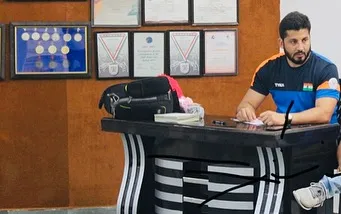 At my desk in the academy, with my own medals and certificates in the background. I lead by example, and my personal achievements are a testament to the path of success I guide my students on.