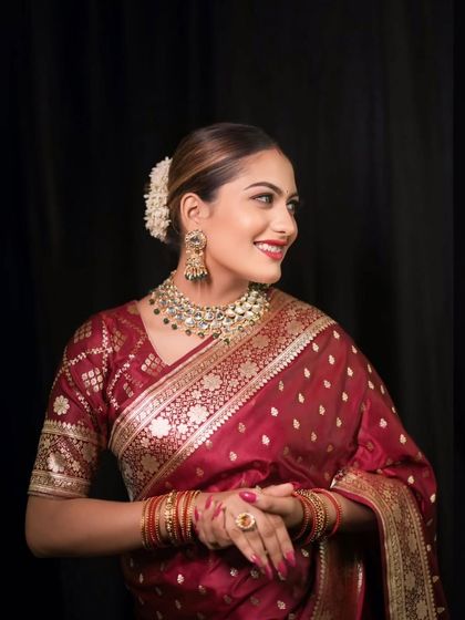 A three-quarter portrait of the bride, showcasing her elegant posture, beautiful saree, and the traditional gajra in her hair.