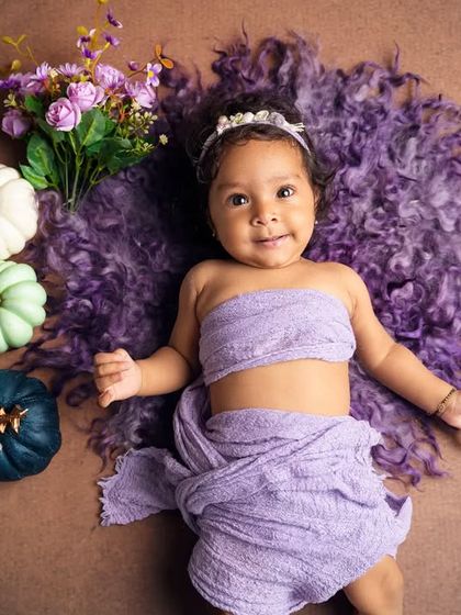This little girl is surrounded by colorful pumpkins and flowers for her six-month sitter session, showing off her curious personality.