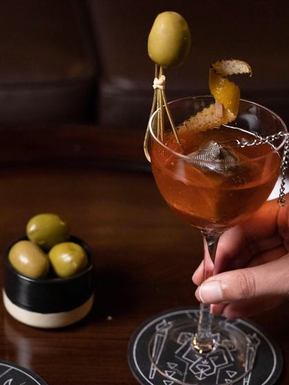 Come and experience an array of unique concoctions. This martini variation is garnished with a large green olive and a twist of lemon, offering a savory and complex profile.