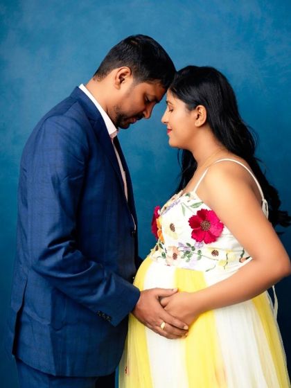 An intimate forehead-to-forehead pose, with the mom-to-be in a beautiful yellow and white floral gown.