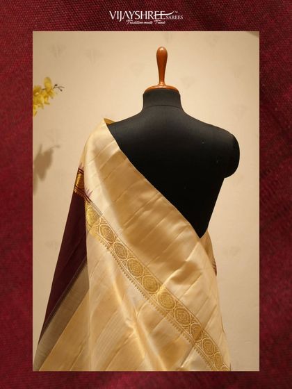 The elegant drape of the cream and maroon Kanjivaram, showing the contrast of the plain body and the heavy zari border.
