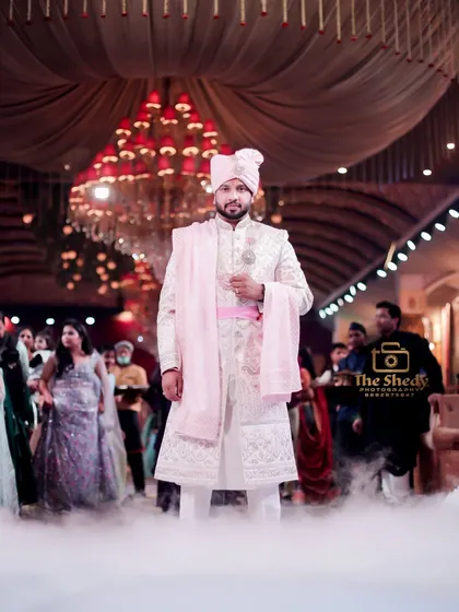 The groom's grand entrance. This shot captures him standing confidently amidst a cloud of dry ice, with the magnificent venue chandelier in the background, creating a truly royal portrait.