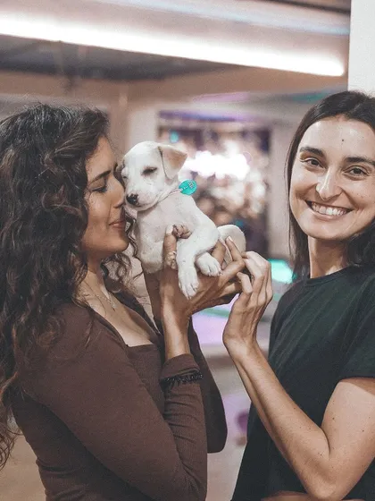 A participant kisses a small white puppy, a beautiful moment that shows why we do what we do. The goal is always to find a home for every puppy.