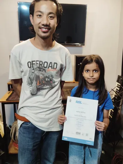 We love celebrating our students' first big wins. Here is our young star Aira with her teacher Ragui, proudly holding her RSL debut exam certificate for ukulele, which she passed with distinction.
