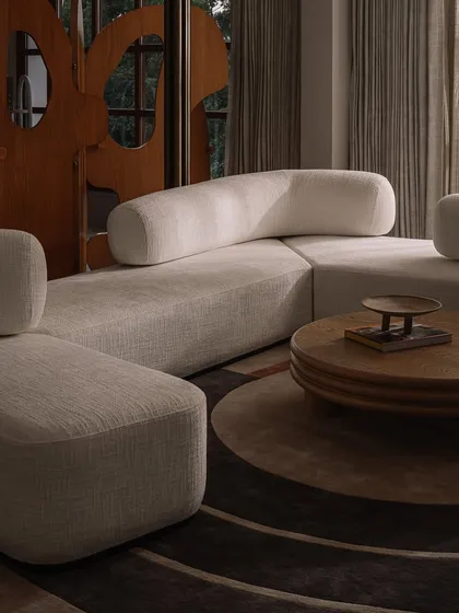 The play of light and shadow on the curved, upholstered forms of this custom sofa highlights its sculptural quality. We focus on creating furniture with soft, inviting silhouettes that anchor a room.