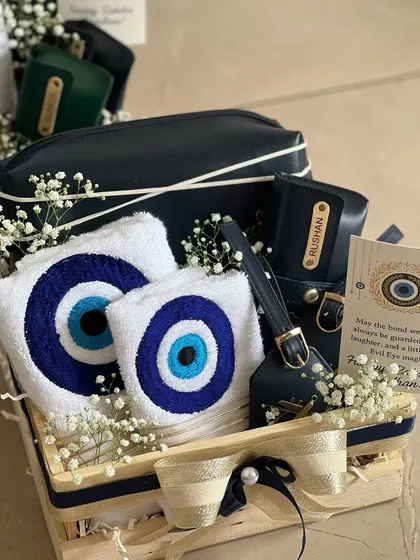 This Evil Eye Rakhi hamper is a complete set for your brother. It includes a personalized pouch, a matching luggage tag, and a soft towel, all featuring the protective symbol.