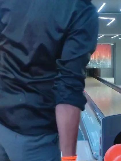 A player in a black shirt focuses on the pins at the end of the lane during one of our competitive bowling tournaments.