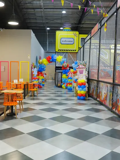 A look down the main walkway during a carnival-themed event. The checkered floor and colorful decorations create a festive and welcoming path for guests.
