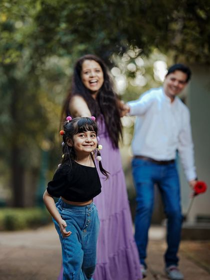 A happy family moment with a little girl leading her parents down a tree-lined path, full of smiles and laughter.