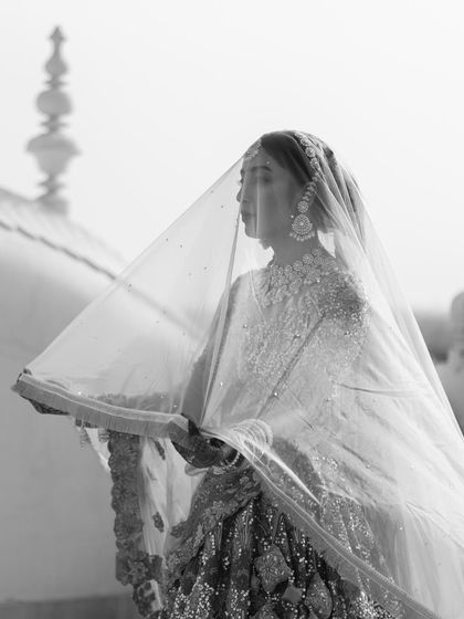 An ethereal black and white portrait of the bride under her veil. The soft focus and the architectural details in the background give this photo a timeless, dreamy quality.