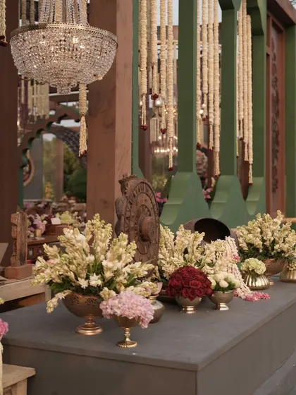 A decor console with beautiful floral arrangements and traditional artifacts, set against the backdrop of a crystal chandelier. These details add richness and character to the space.