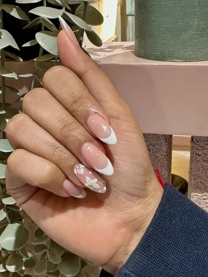 A close-up on the delicate, hand-painted flower that elevates this French manicure from classic to custom.