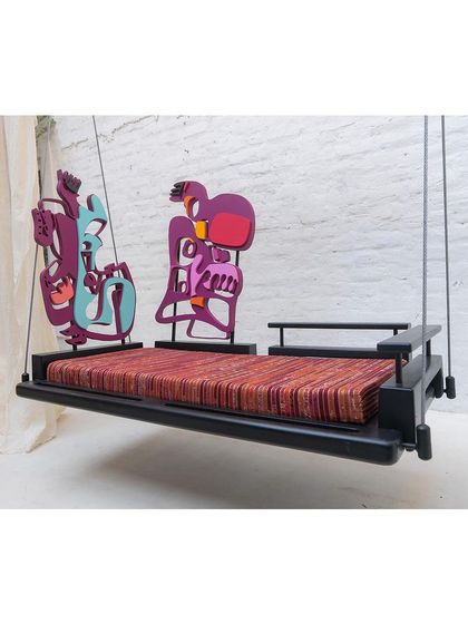 An angled view of the 'Kaleidochaos' swing, highlighting its sleek teakwood frame and vibrant artistic elements.