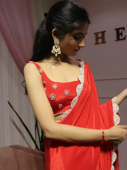 A close-up of the model wearing the red saree, showing the delicate scalloped border.