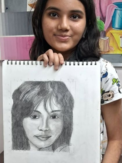 A student from our human anatomy class proudly displays her finished pencil shading portrait. She has successfully captured the subject's expression and hair texture.