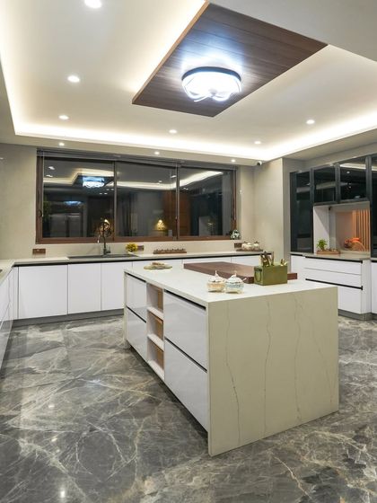 The spacious island in the Jains' kitchen is the heart of the room, providing storage, a prep surface, and a place for the family to gather. The marble-patterned floor adds a touch of classic elegance.