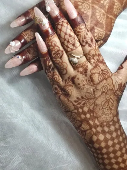 This is a beautiful example of festive nails created by one of our students for Karwa Chauth. The soft pink extensions with delicate 3D white flowers and nail jewelry perfectly match the intricate henna.