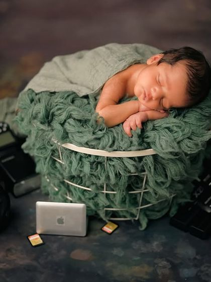 Another perspective of the 'Baby Director' shoot. This angle shows the newborn peacefully sleeping, surrounded by all the tools of the photography trade.