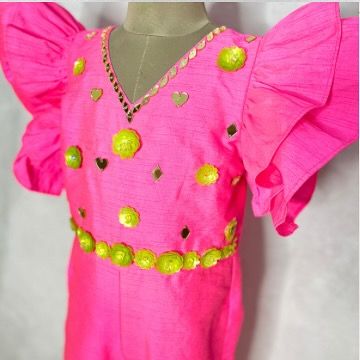 A close-up of the bodice of the pink jumpsuit, with its playful mix of sequins and embroidered details.