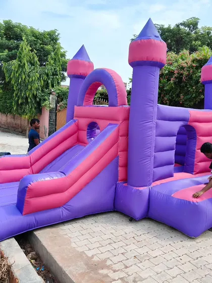 A full view of the pink and purple princess castle, showing the main jumping area, climbing ramp, and slide.