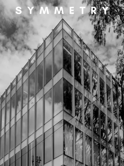City reflections, perfect geometry. This black and white image of a commercial glass facade highlights how symmetry is not just seen, but felt.