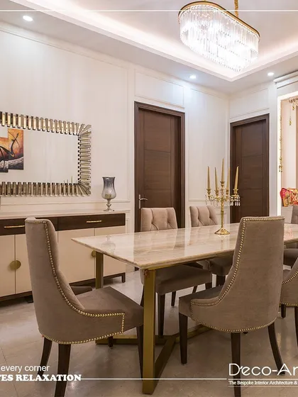 An elegant fusion of modern minimalism and classic detailing. This dining space features a sleek marble-top table, neutral-toned upholstery, and a statement chandelier to complete a look of sophisticated dining.