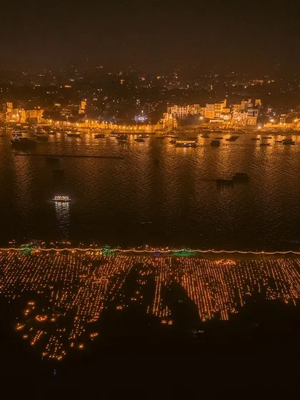 An aerial view of the ghats of Varanasi during Dev Deepawali. The entire riverfront is lit up with thousands of diyas, creating a river of light.