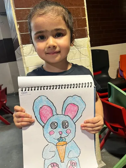 This little artist is so proud of her bunny drawing, and she should be. We focus on making art fun and rewarding, encouraging creativity with every colorful sketch.