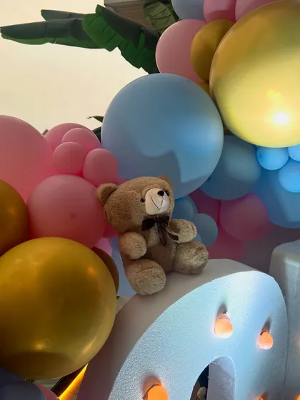 This whimsical baby shower featured large marquee letters, teddy bears nestled in pastel balloon clouds, and a custom hot air balloon prop, creating a dreamy and joyful atmosphere.