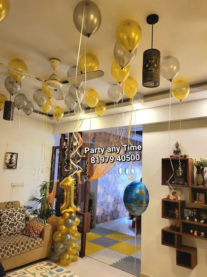Gold and silver helium balloons floating in a living room for a first birthday celebration.