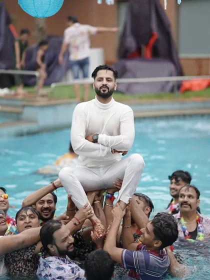 The groom being lifted up by his friends during a pool party. These celebrations are all about high energy and unforgettable moments with your loved ones.