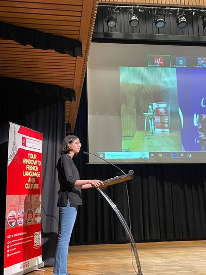 A student confidently presents on stage during the "Read Aloud" competition. We provide a platform for students to build their public speaking skills.