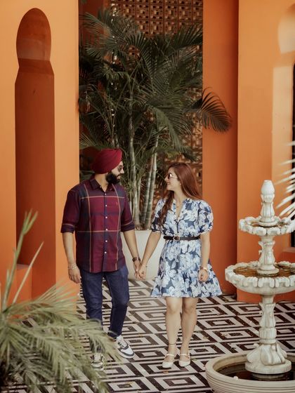A candid shot of the couple walking hand-in-hand through a colorful, Moroccan-inspired courtyard. Their casual outfits and happy interaction create a relaxed, vacation-like feel.