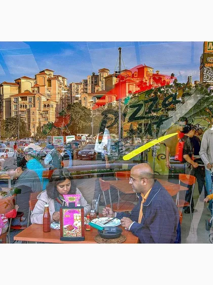 A reflection captures the busy life of a city street and the quiet moment of a family dining inside a Pizza Hut. This image juxtaposes the public and private spheres of urban life.