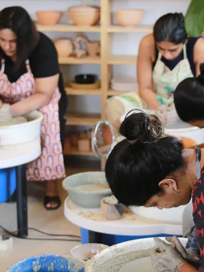 A group of students fully immersed in their work at the pottery wheels, a typical scene of focused creativity at our studio.