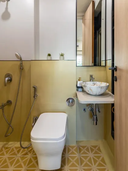 A compact bathroom design featuring geometric yellow floor tiles, a marble-finish vessel sink, and a space-saving vanity.