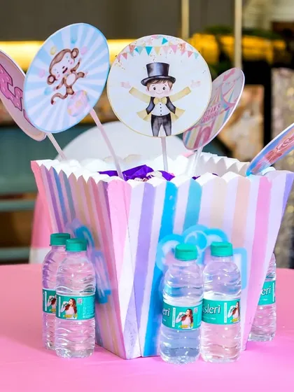 A themed centerpiece with carnival-style cutouts and bottled water for guests.